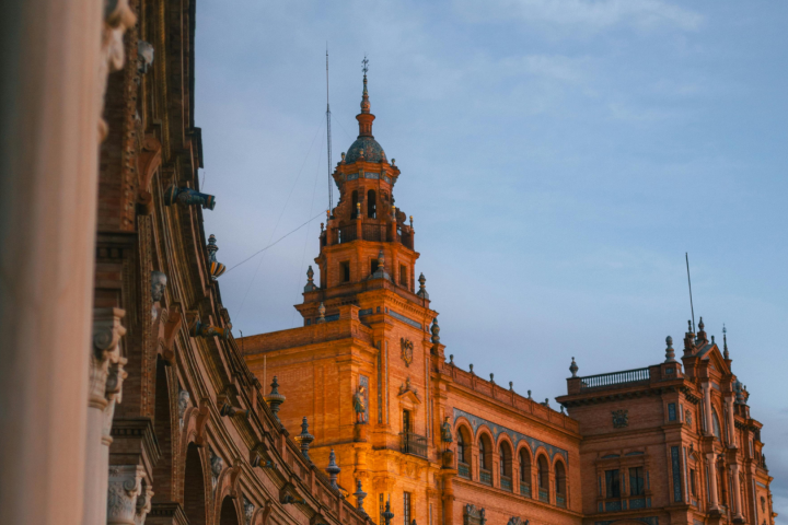 Historic building with ornate tower and arches under a twilight sky.