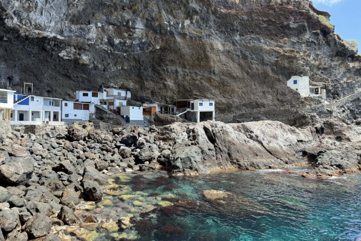 Seaside cliff with small white buildings and rocky shoreline.