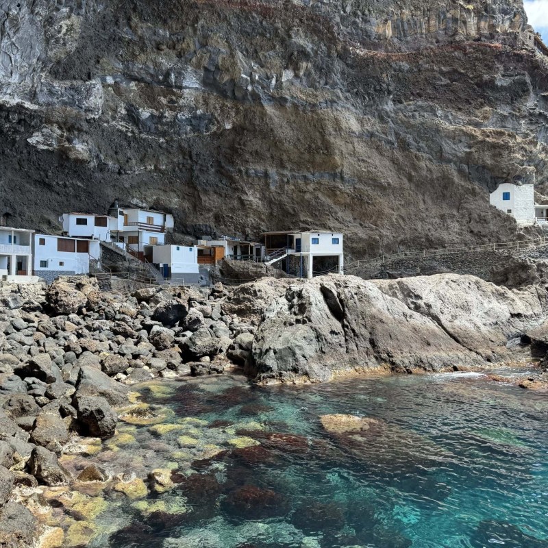 Seaside cliff with small white buildings and rocky shoreline.