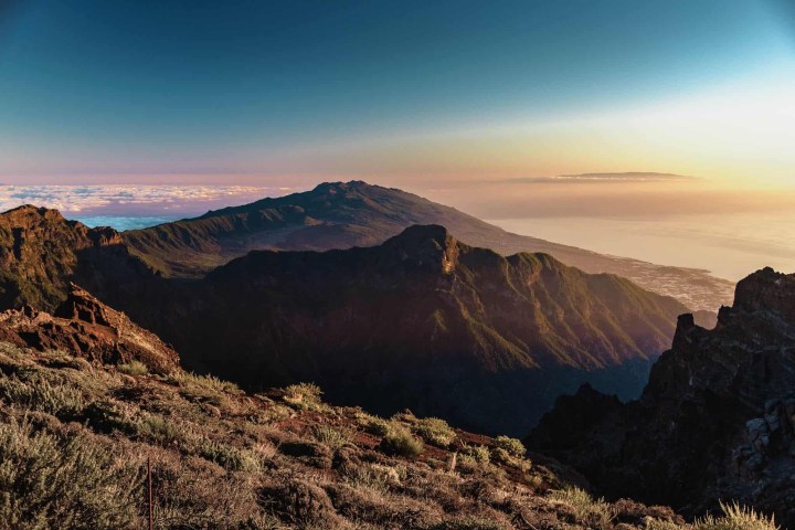 Scenic mountain landscape at sunrise with distant ocean view.