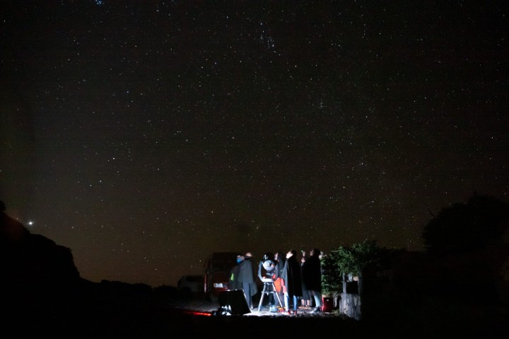 Group stargazing with telescope under a clear night sky.